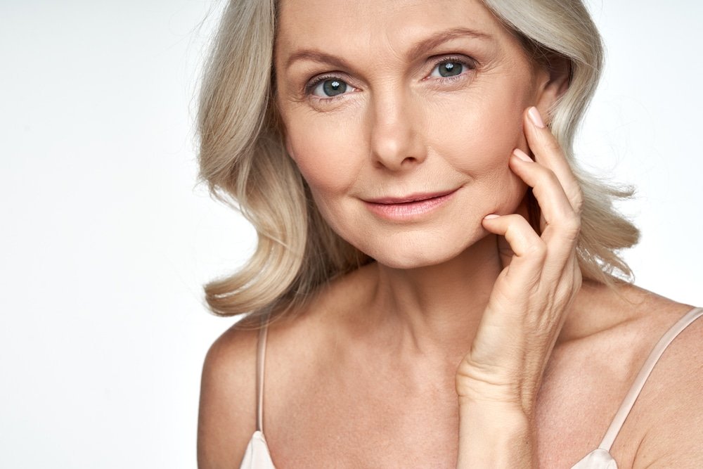 50s,Mid,Aged,Woman,Touching,Face,Skin,Looking,At,Camera.