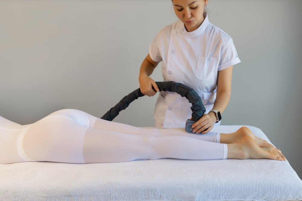 Vrouw krijgt lipo massage behandeling voor benen en billen met speciaal apparaat tegen cellulite